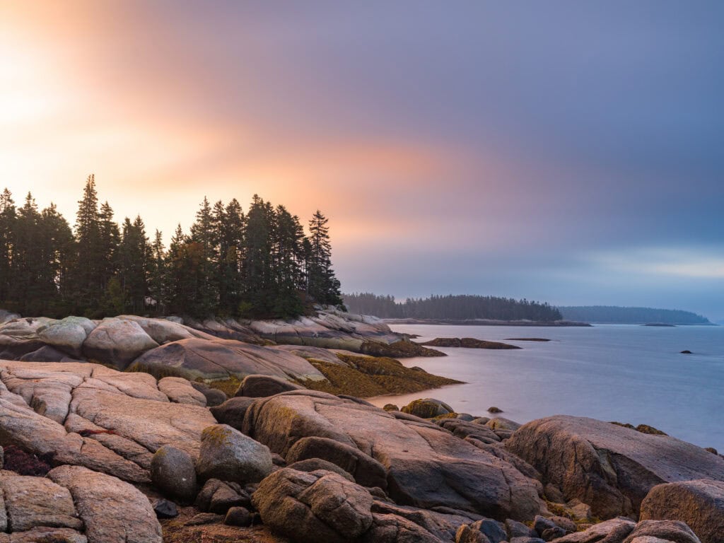 Hypnopompia color long exposure photograph of dawn light and fog over pink granite coast with spruce treeline, Sand Beach, Stonington, Maine, fine art landscape photography by Brad Emerson