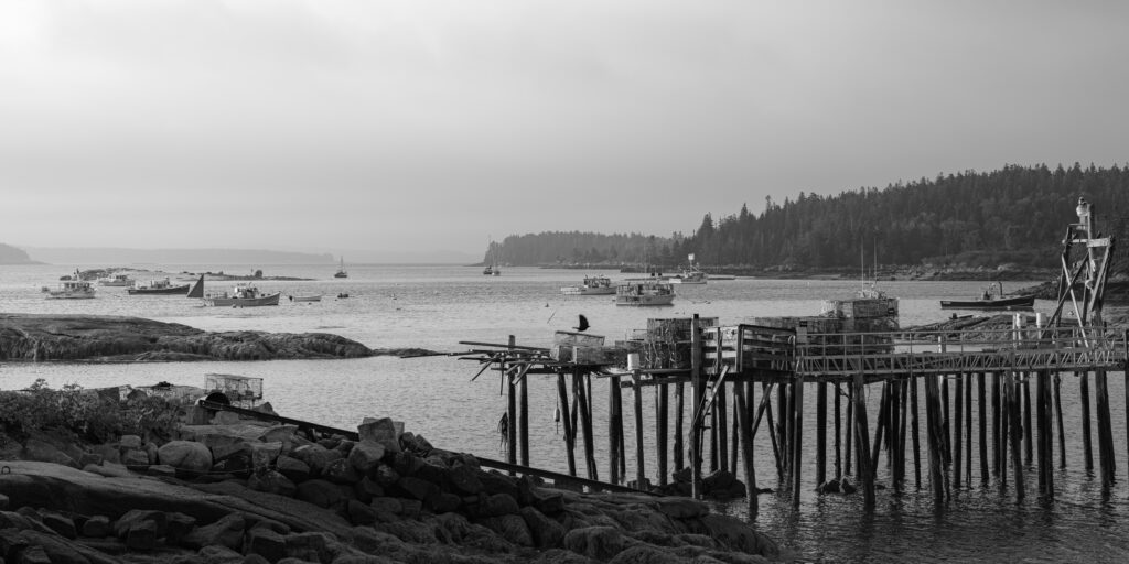 Slack Tide black and white photograph of lobster boats at anchor and weathered dock pilings at slack tide, Stonington, Maine, fine art landscape photography by Brad Emerson