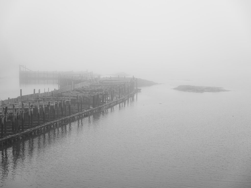 The Weir black and white photograph of traditional herring weir structures receding into dense fog, Stonington, Maine, fine art landscape photography by Brad Emerson